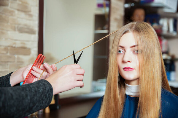 Парикмахер делает прическу ножницами
