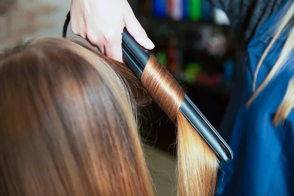 Hairdresser making hairstyle with curling iron — Stock Photo, Image
