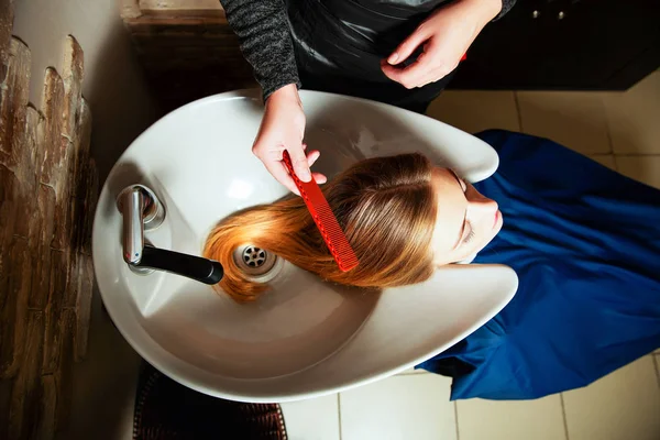 젊은 여자의 머리카락을 세척 하는 미용사 — 스톡 사진