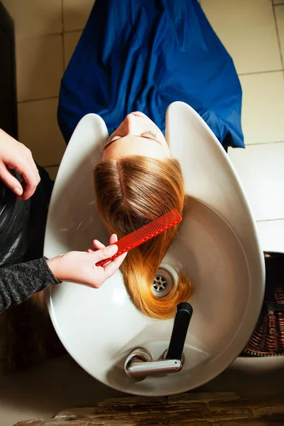 Hairdresser washing young woman's hair — Stock Photo, Image