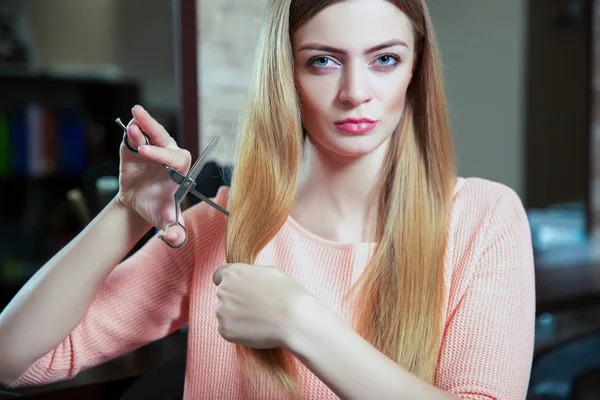 Молодая женщина с ножницами стрижет волосы — стоковое фото