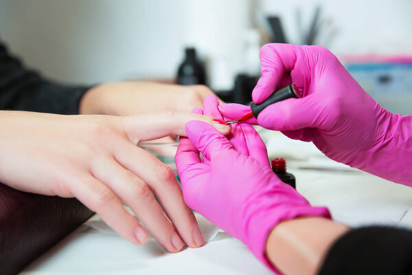 Manicurist applies nail polish on nails