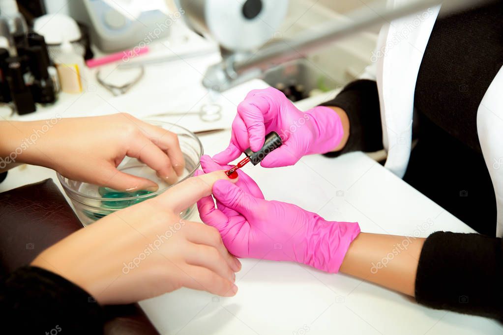 Manicurist applies nail polish on nails