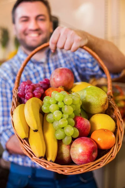 Sprzedawca, trzymając Wiklinowy kosz z owocami — Zdjęcie stockowe