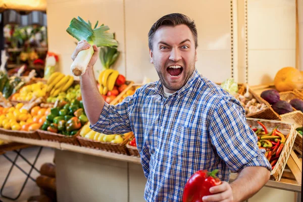 Man jokes with leek and pepper in hands — Stock Photo, Image