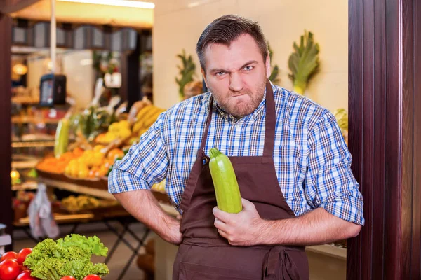 Seller holds vegetable marrow in hand — Stock Photo, Image