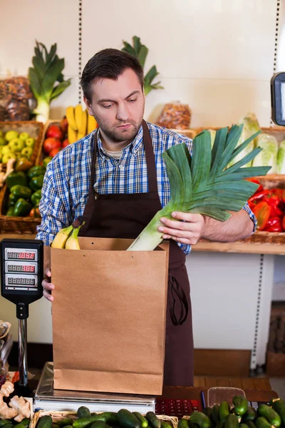 Venditore in grembiule mette gli acquisti in pacchetto — Foto Stock