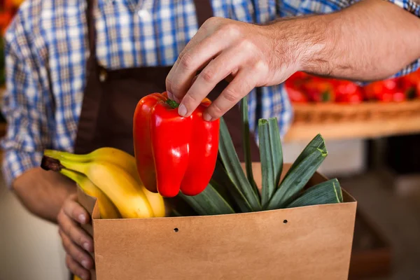 Säljare i förkläde sätter inköp i paketet — Stockfoto