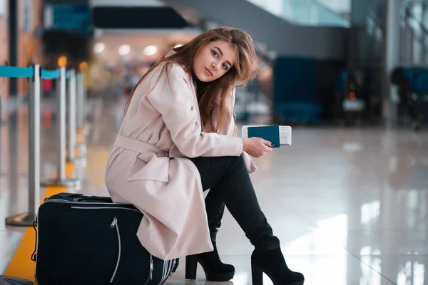 Woman sitting on suitcase in airport terminal — Stock Photo, Image