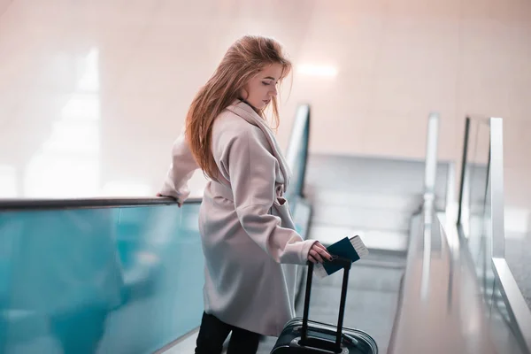 Женщина с чемоданом спускается по эскалатору — стоковое фото