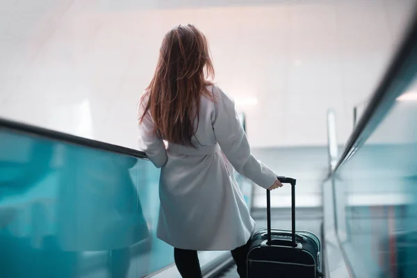 Woman with suitcase moving down escalator — Stock Photo, Image