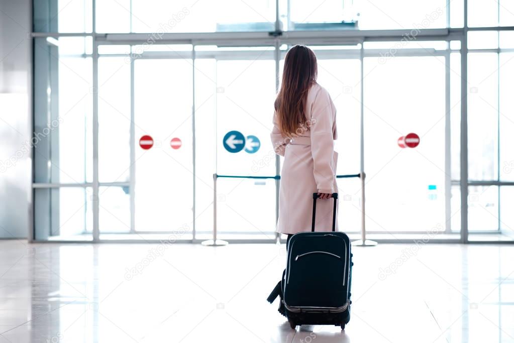 woman with suitcase going to exit of airport