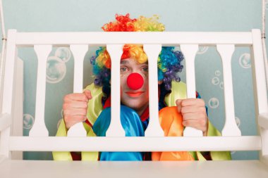 Punished clown sitting under bench clipart