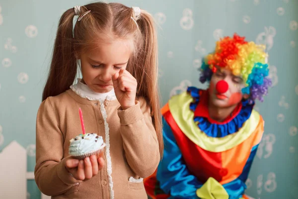 Girl holding cupcake with candle and crying — Stock Photo, Image