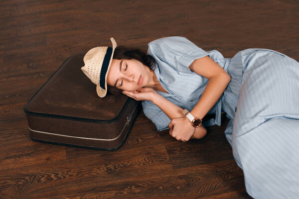 Женщина спит с головой на чемодане
