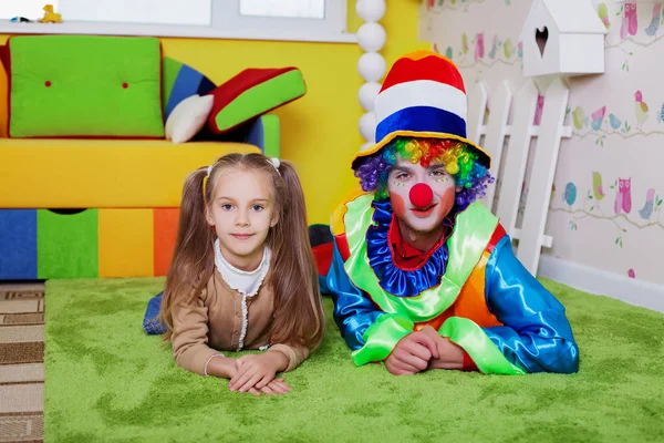 Menina e palhaço mentira no tapete — Fotografia de Stock