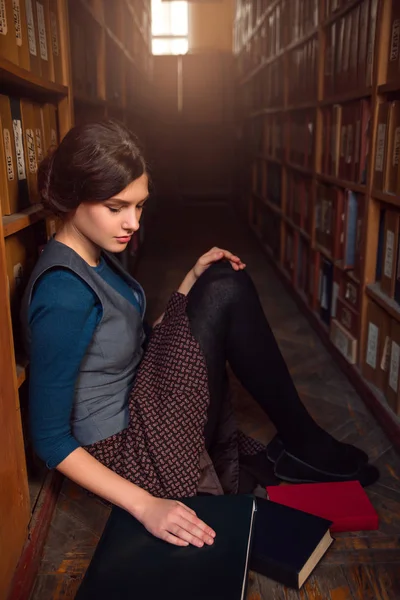 Giovane donna seduta al piano in biblioteca — Foto Stock