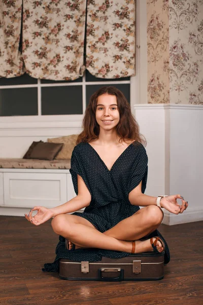 Ung kvinna mediterar på resväska — Stockfoto