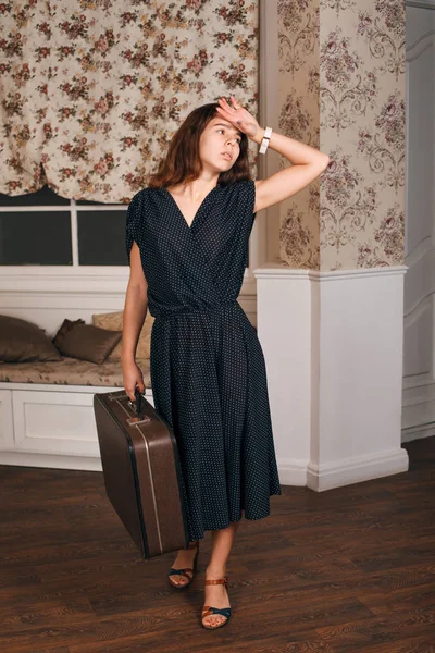 Νεαρή γυναίκα με μαύρο φόρεμα με βαλίτσα — Φωτογραφία Αρχείου