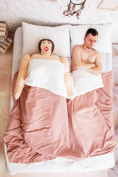Грустный мужчина просыпается с секс-куклой — стоковое фото