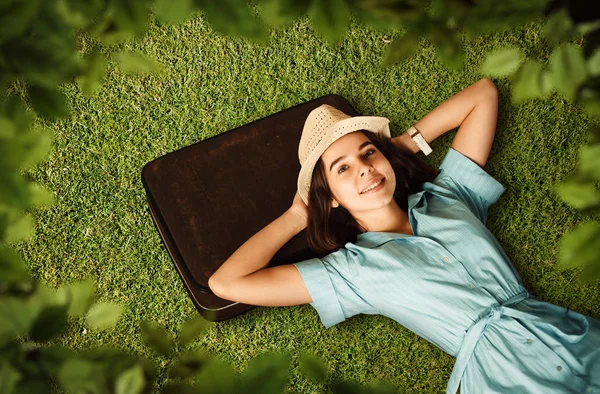 Jeune femme souriante avec la tête sur la valise — Photo