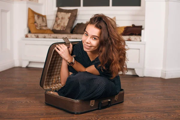Молодая женщина пытается забраться в чемодан — стоковое фото