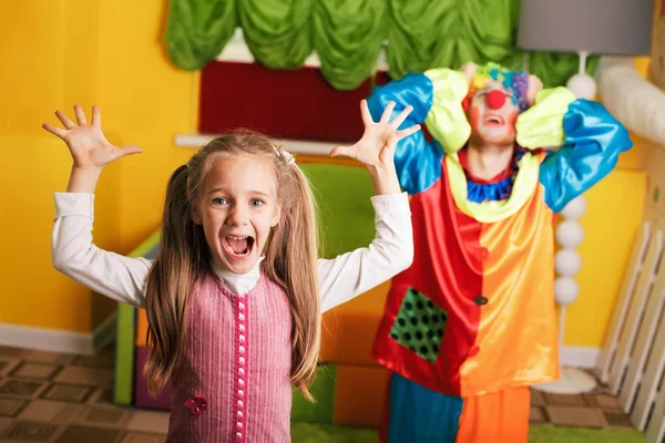 Маленька дівчинка грає з засмученим клоуном — стокове фото