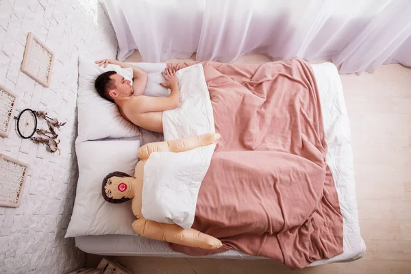 Homem dormindo na cama com sexo boneca — Fotografia de Stock