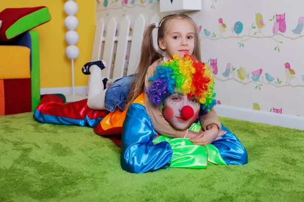 Liten flicka sitter på baksidan av clown — Stockfoto