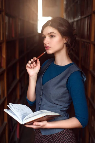 Mujer joven con cuaderno en la biblioteca —  Fotos de Stock