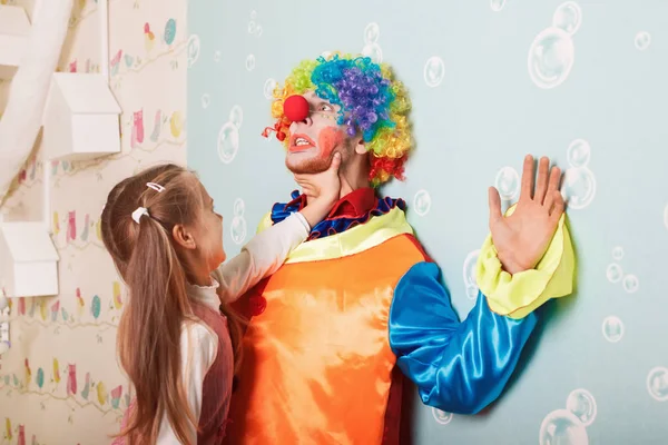 Grym liten flicka som leker med clown — Stockfoto