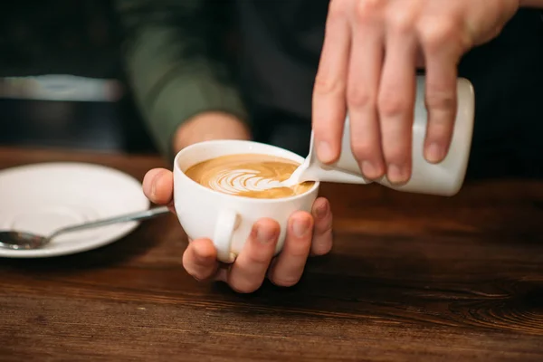 Manos masculinas agregando crema al café — Foto de Stock