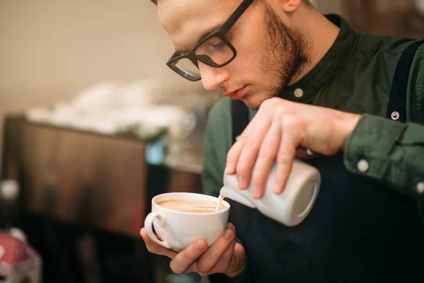 Mãos masculinas adicionando creme ao café — Fotografia de Stock