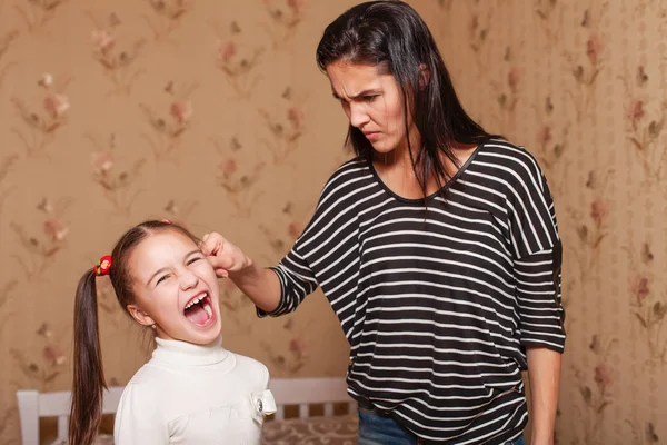 Angry mother holding ear of daughter — Stock Photo, Image