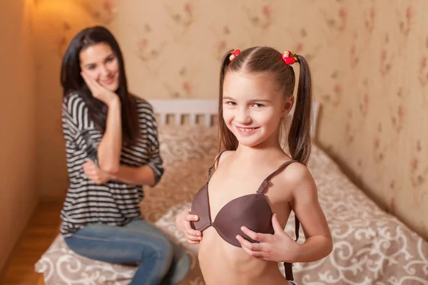 Маленька дівчинка намагається на коричневому бюстгальтері — стокове фото