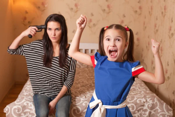 Niña tonteando y madre con pistola — Foto de Stock