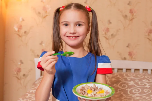 Mädchen hält Teller mit Haferbrei und Löffel — Stockfoto