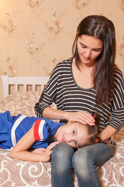 Pequena filha deitada em voltas de mãe — Fotografia de Stock