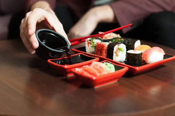 Homem comendo sushi com pauzinhos — Fotografia de Stock