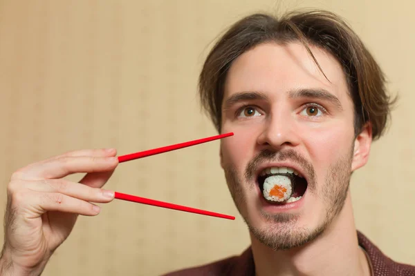Jonge man eats sushi — Stockfoto