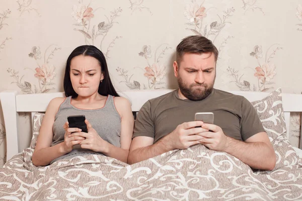 Couple utilisant des téléphones mobiles au lit — Photo