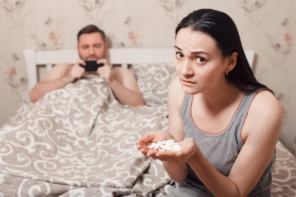 Esposa tratando de comer tabletas en la cama —  Fotos de Stock