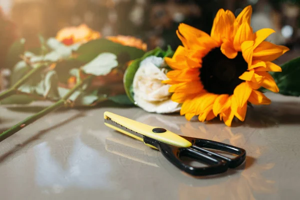 Scissors with roses and sunflower on grey table — Stock Photo, Image