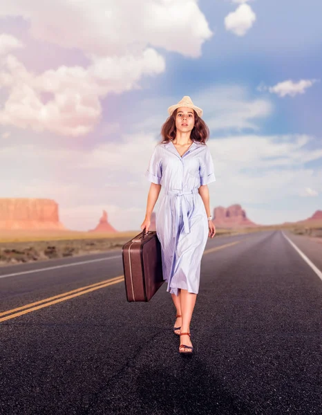 Mujer joven con equipaje caminando por la carretera — Foto de Stock