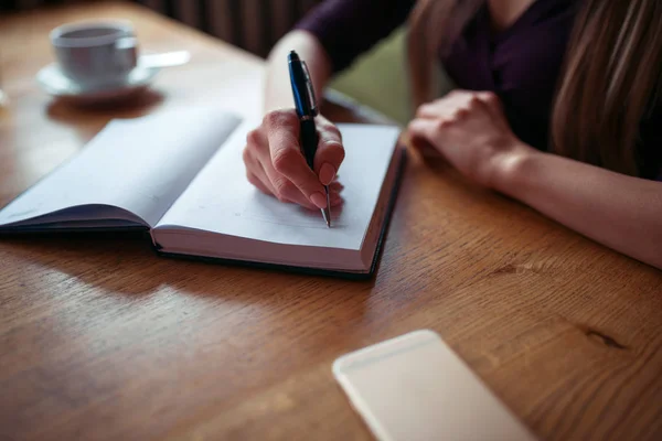 Jonge vrouw schrijven in notebook — Stockfoto