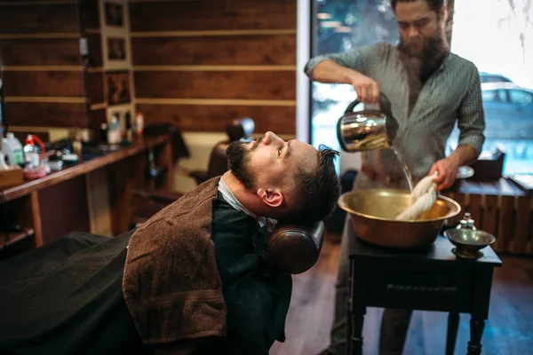 Homem barbudo e barbeiro na barbearia — Fotografia de Stock