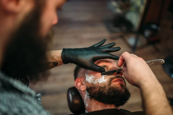 Парикмахерская бреющая борода клиента — стоковое фото