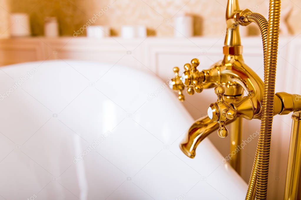 shining golden faucet and white bath