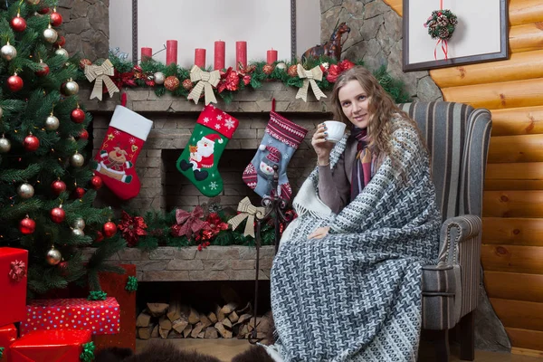 Woman wrapped in plaid near fireplace — Stock Photo, Image