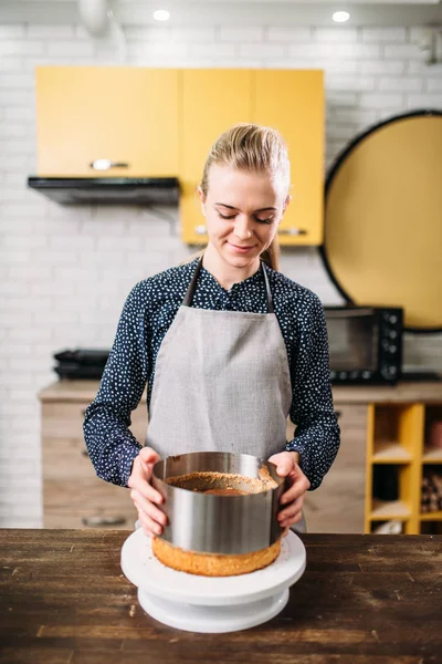 woman holding cooking ring with cake